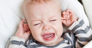 Baby crying and pulling at their ears.